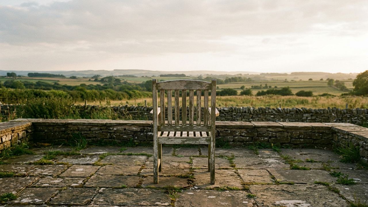 One plain wooden chair on a stone terrace facing open country, a second chair absent, low evening light